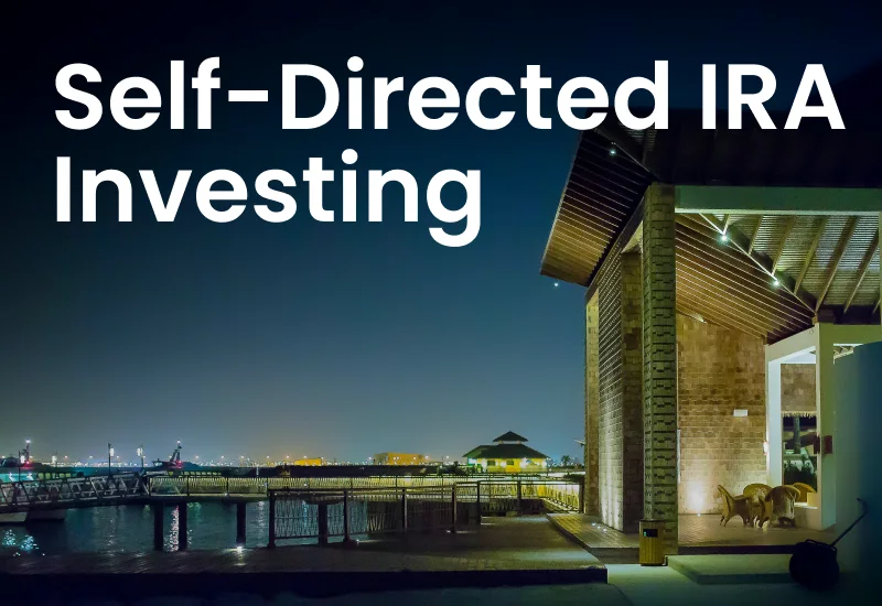 A timber building lit at night beside a waterfront walkway, with the words Self-Directed IRA Investing across it